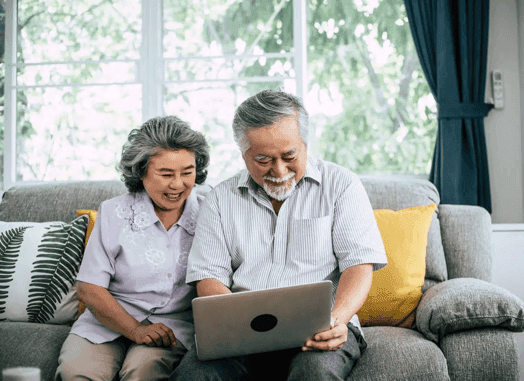 Smiling senior couple reviewing Medicare options on a laptop